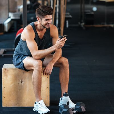 Fitness man sits on the box with phone