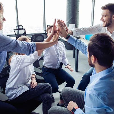 High-five! cheerful young business people giving high-five while their colleagues looking at them and smiling.